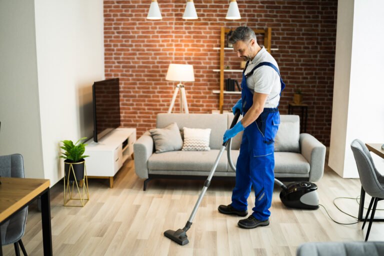 a man cleaning a hardwood floor with vacuum cleaner in his leaving room