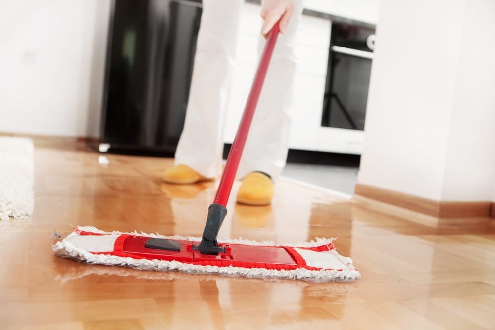 A Girl Cleaning Hardwood floor with a mop. Images showes a clean and shiny hardwood floor