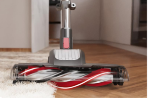 Close-up view of the brush head of the Roomie Tec Dylon Cordless Vacuum Cleaner, transitioning smoothly from a hardwood floor to a soft carpet, highlighting its versatile cleaning capabilities.